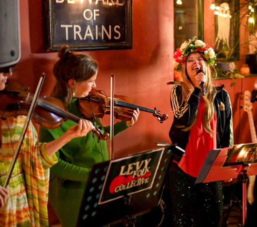 Folk musicians in festive attire performing with violins and in a lively ceilidh.